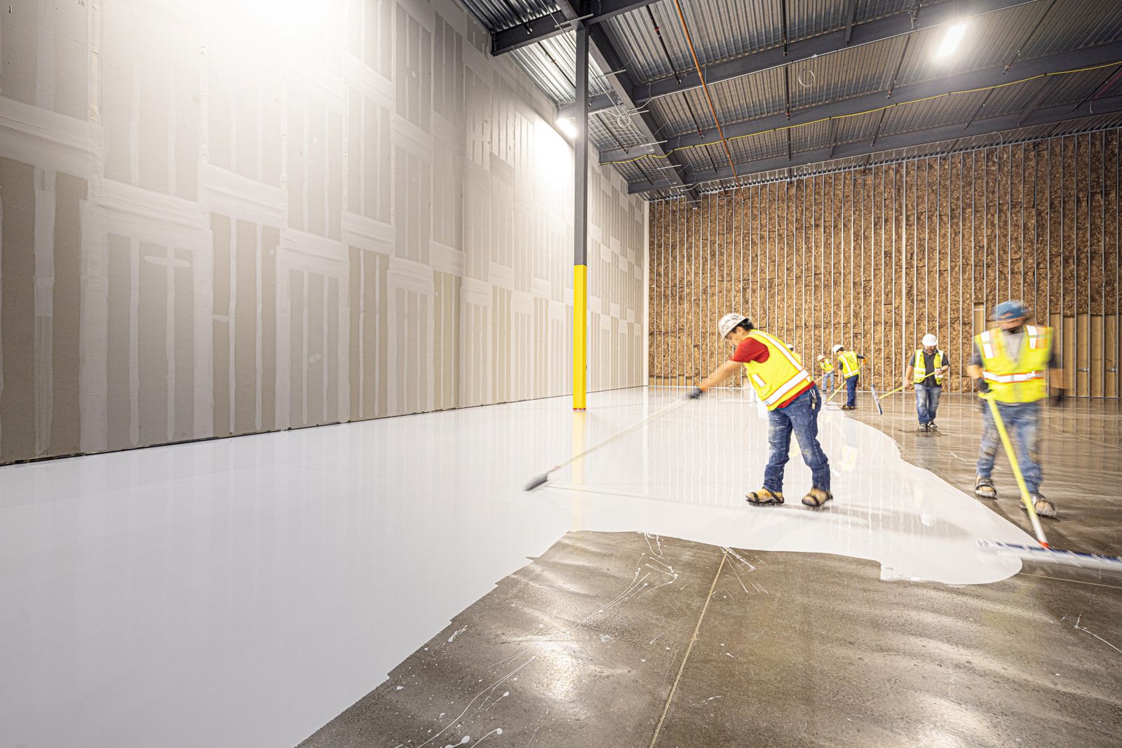 How long does a garage floor coating last: crew applying coating over prepped concrete