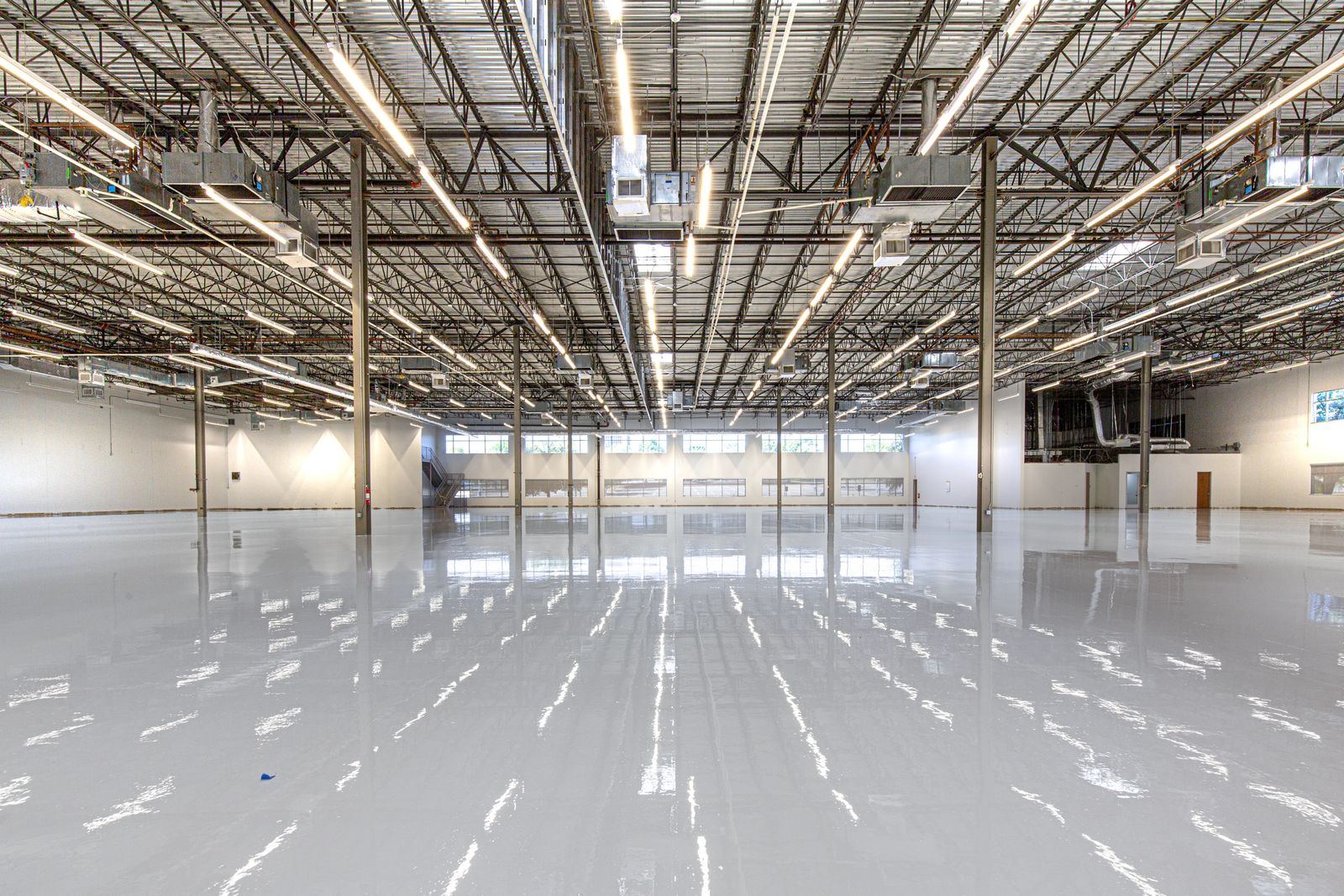 High gloss epoxy coated floor reflecting the ceiling lights across an empty warehouse