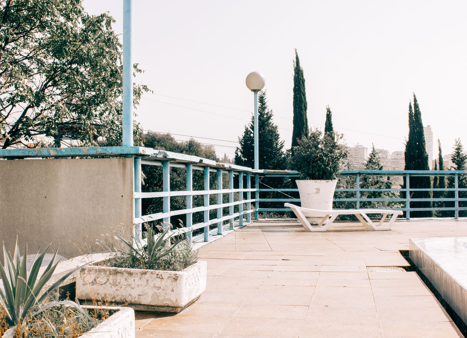 Outdoor terrace with a smooth slab, planters, and a lounge chair, the kind of surface people mean when they ask can you coat a concrete patio
