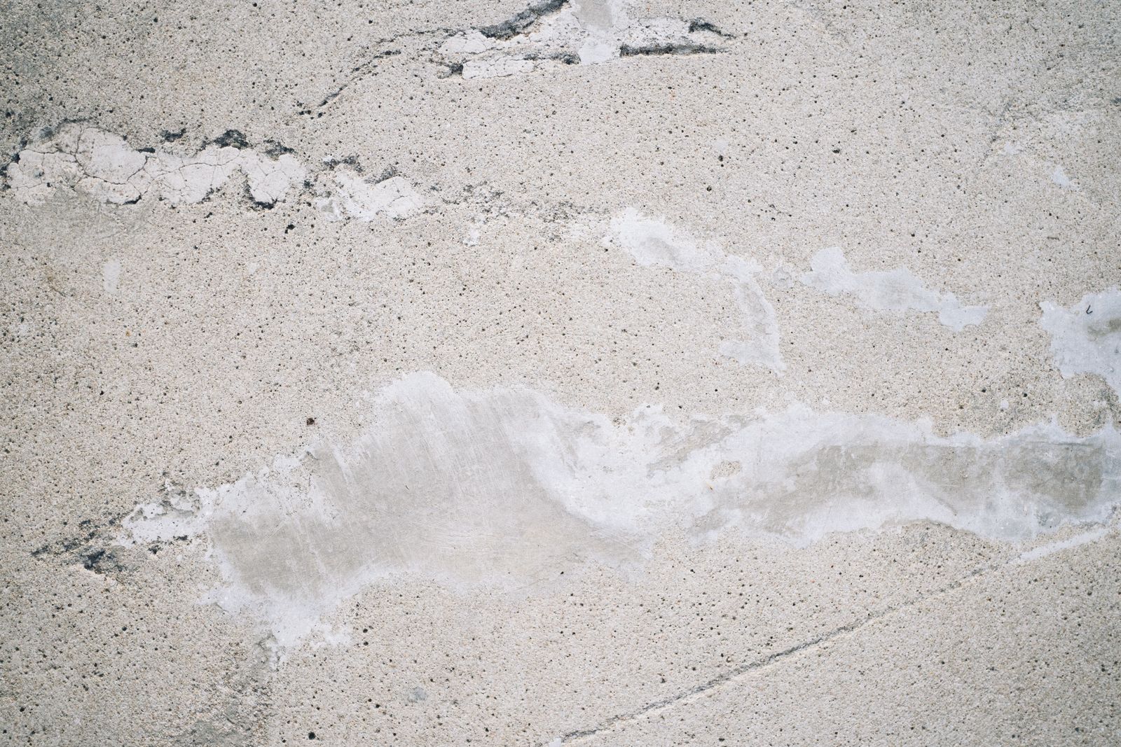 Close-up of a cracked and patched concrete slab, the starting point when asking can you coat a cracked garage floor