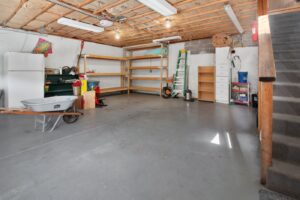 Residential garage interior with storage shelving and a bare concrete floor