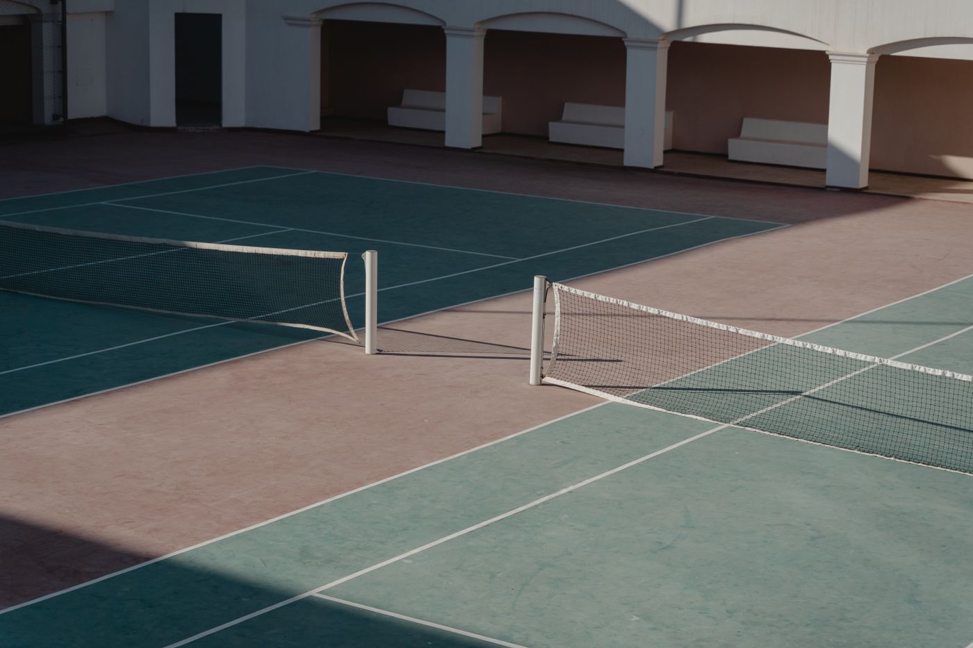 Empty outdoor court with the net casting shadows across the playing surface
