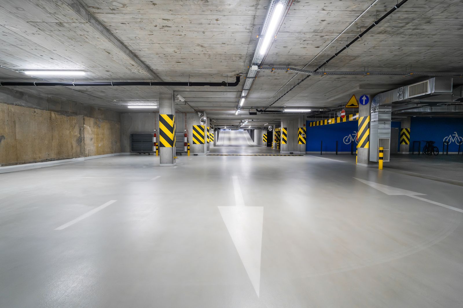Light gray coated concrete floor in a parking garage with painted arrows