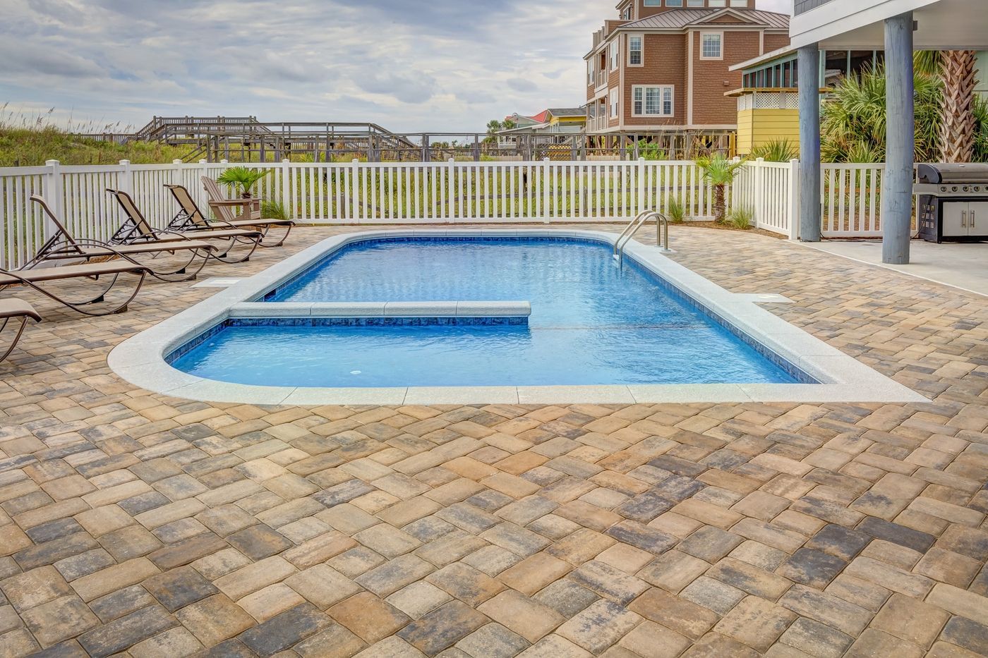 Poolside patio deck with sun loungers beside the water