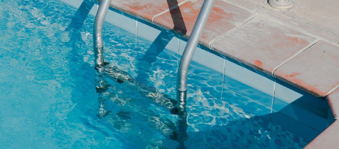 Bright pool deck with a metal ladder and a finished walking surface