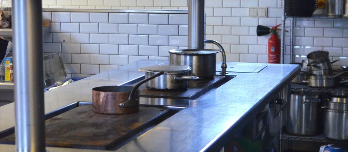 Empty commercial kitchen with stainless steel equipment and a hard floor surface