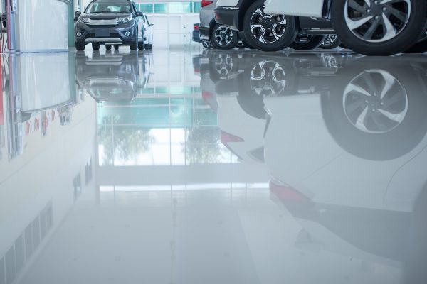 Modern beautiful showroom with cars being sold.  The underside of a car is reflected by the smooth